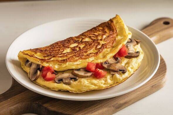 A fluffy omelet filled with sliced mushrooms and diced tomatoes