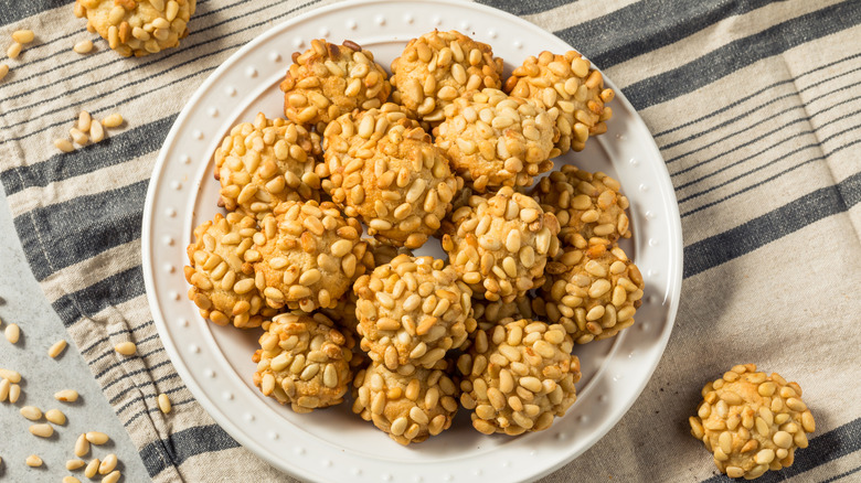 A plate of homemade pignoli cookies resting on a tablecloth