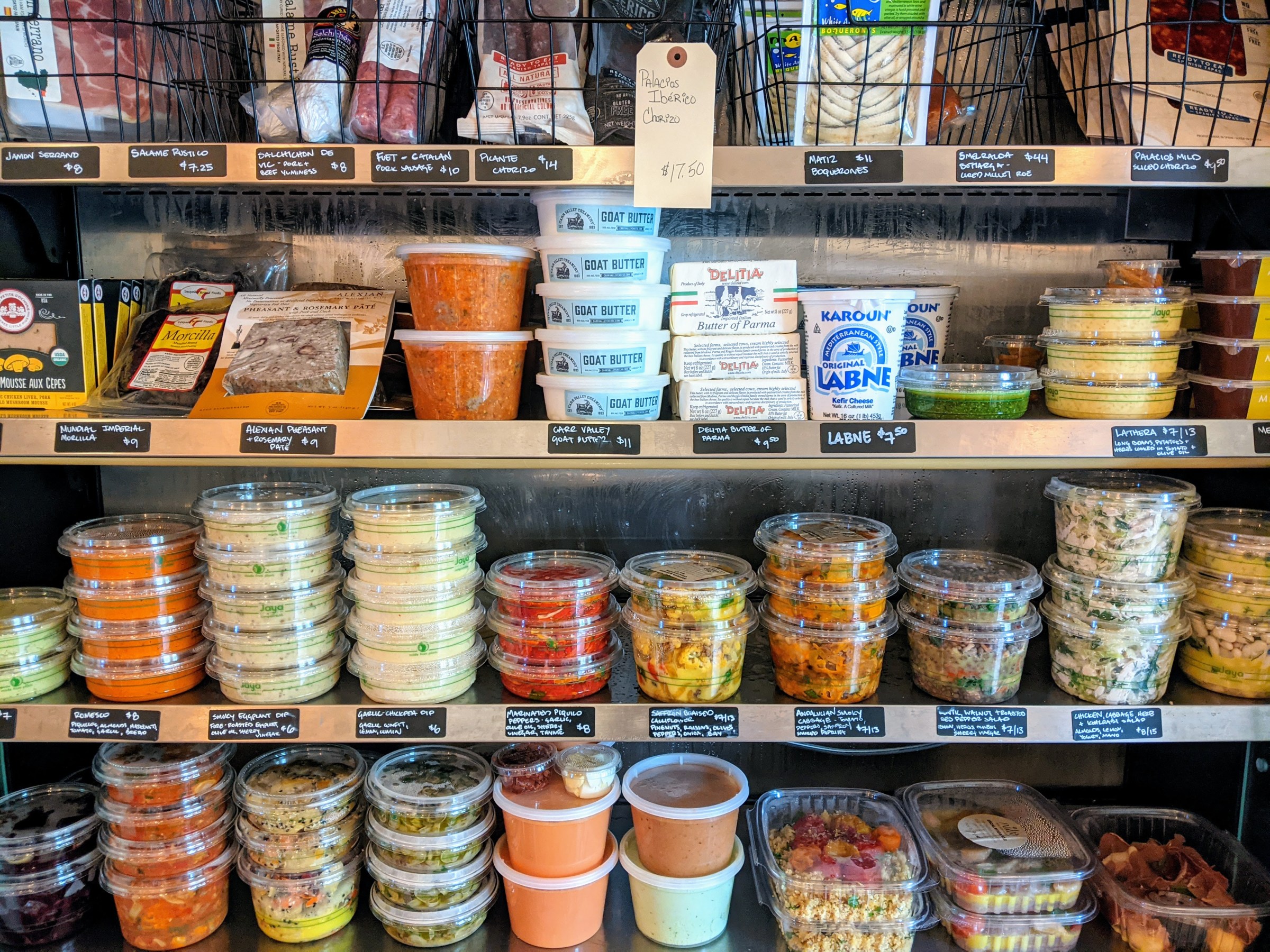 Plastic containers of labneh, meats, and dips fill out rows of shelves at Nido.