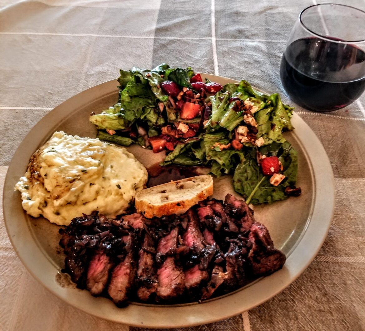 Sirloin steak with red wine sauce, mashed potatoes, and a strawberry goat cheese salad with vinaigrette