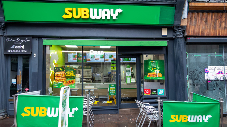 Exterior of a Subway restaurant with outdoor tables
