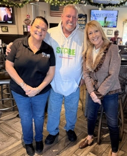 Dena Franks and Roger Mort, co-owners of The Store Bar & Grill in Torrington, are hosting a Charity Chicken Wing Fest thorough March 15, 2026 to benefit the Friendly Hands Food Bank led by Executive Director Karen Thomas (right). (Courtesy)