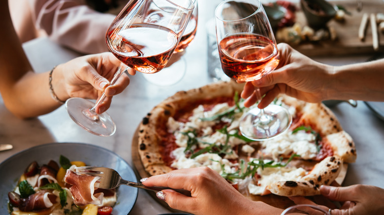 hands holding wine and picking at food