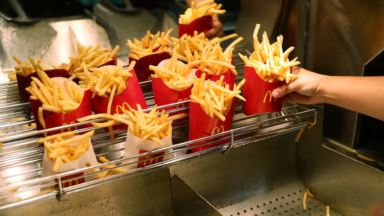 McDonald's staff arranging cartons of fries on metal rack