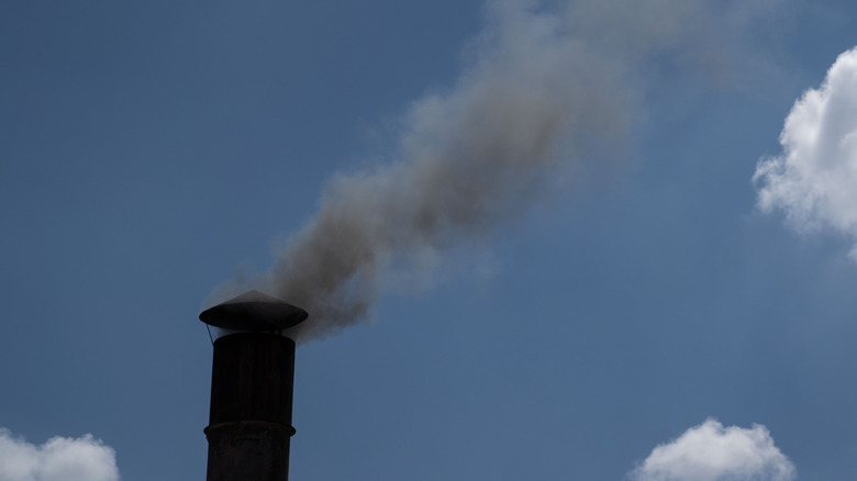 Smoke coming out of a restaurant chimney in front of a cloudy blue sky