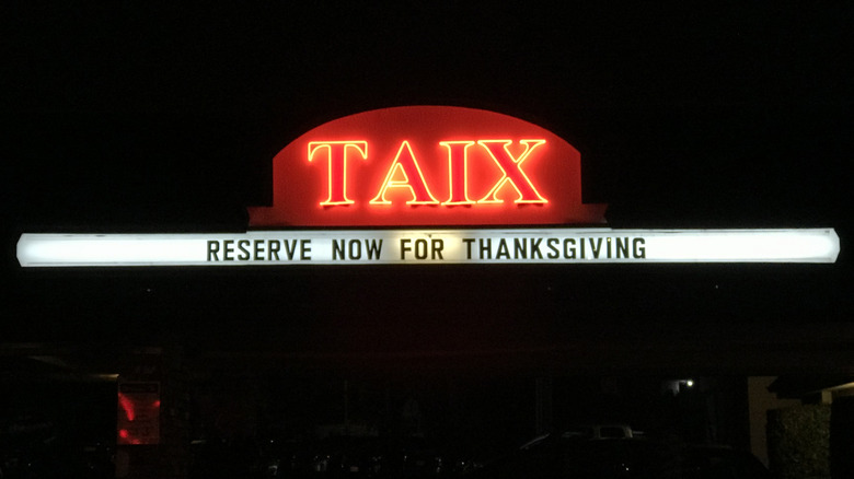 Red neon Taix sign glowing in the dark