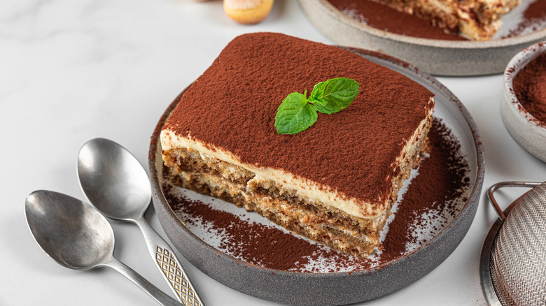 Tiramisu served in gray bowl with silver spoons
