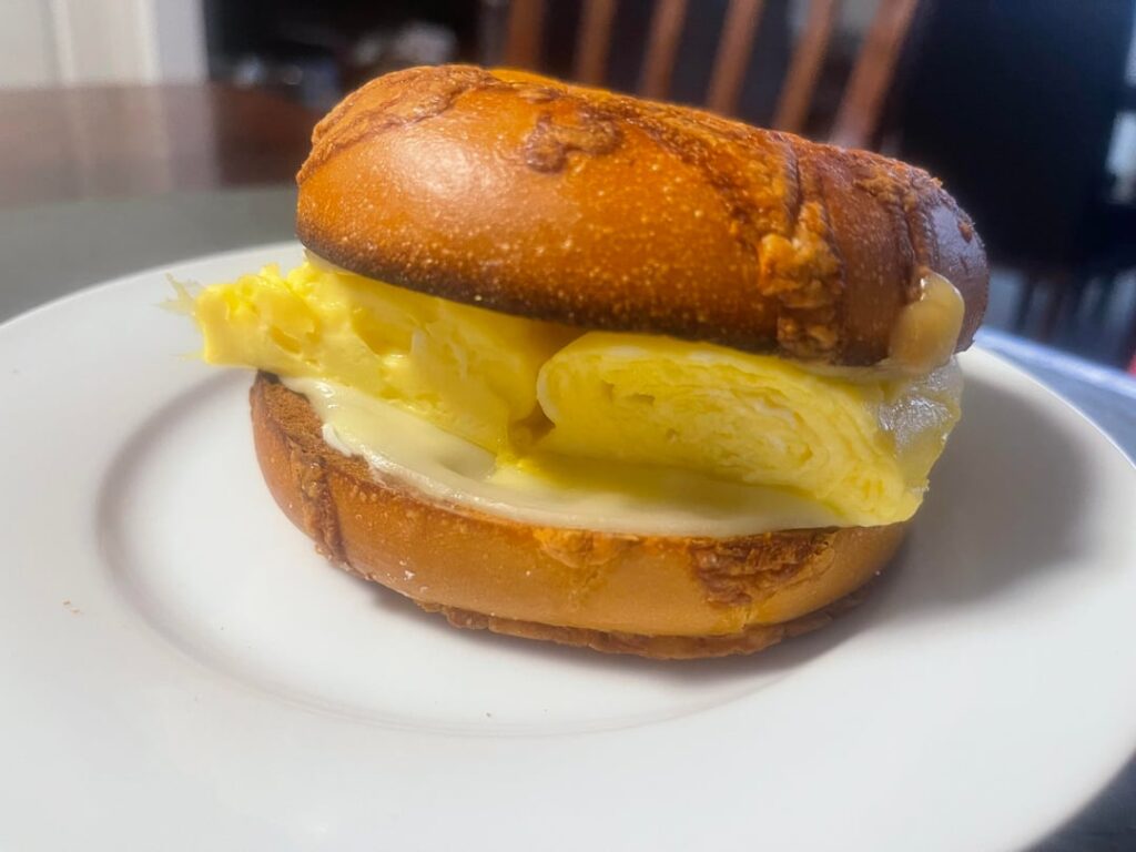 Toasted Asiago cheese bagel with Neufchâtel cheese spread on both slices. Slice of provolone on one side, slice of Gouda on the other. Eggs were made Japanese tamago-style.