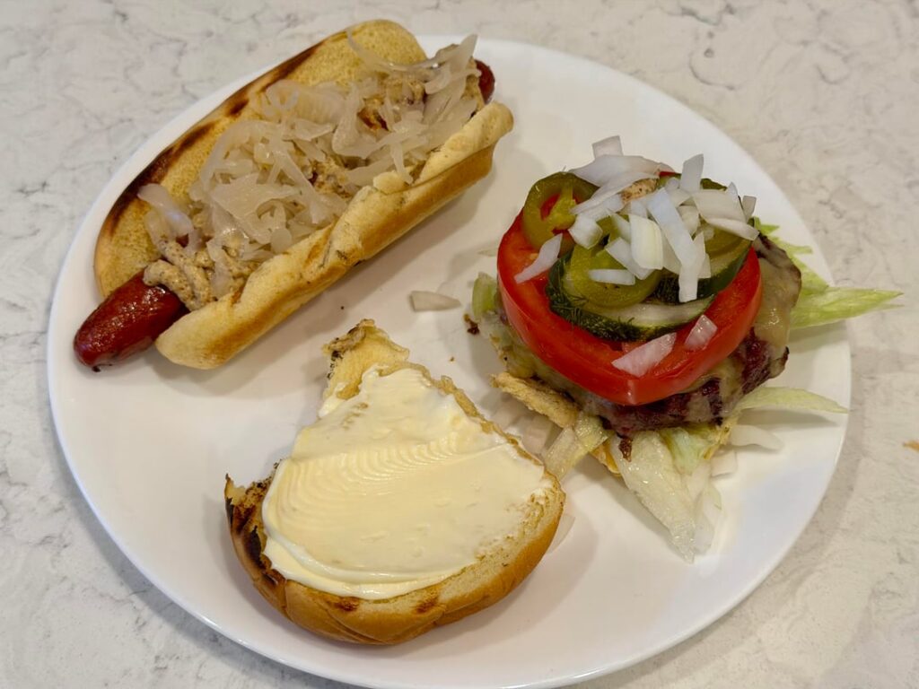 Grilled Pepper-Jack Cheeseburger with shredded iceberg lettuce, sliced tomato, chopped onions, Grillo’s pickles, pickled jalapeño, and Duke’s mayo on toasted potato roll (served with a nice grilled uncured hotdog with spicy mustard and sauerkraut)