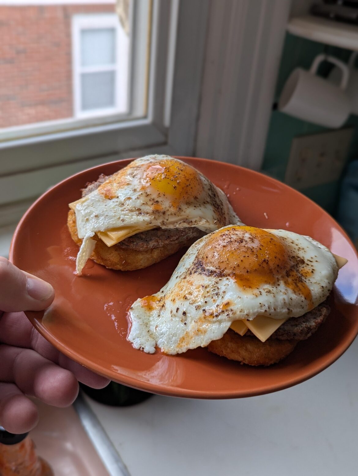 Over easy eggs atop hashbrowns and sausage patties