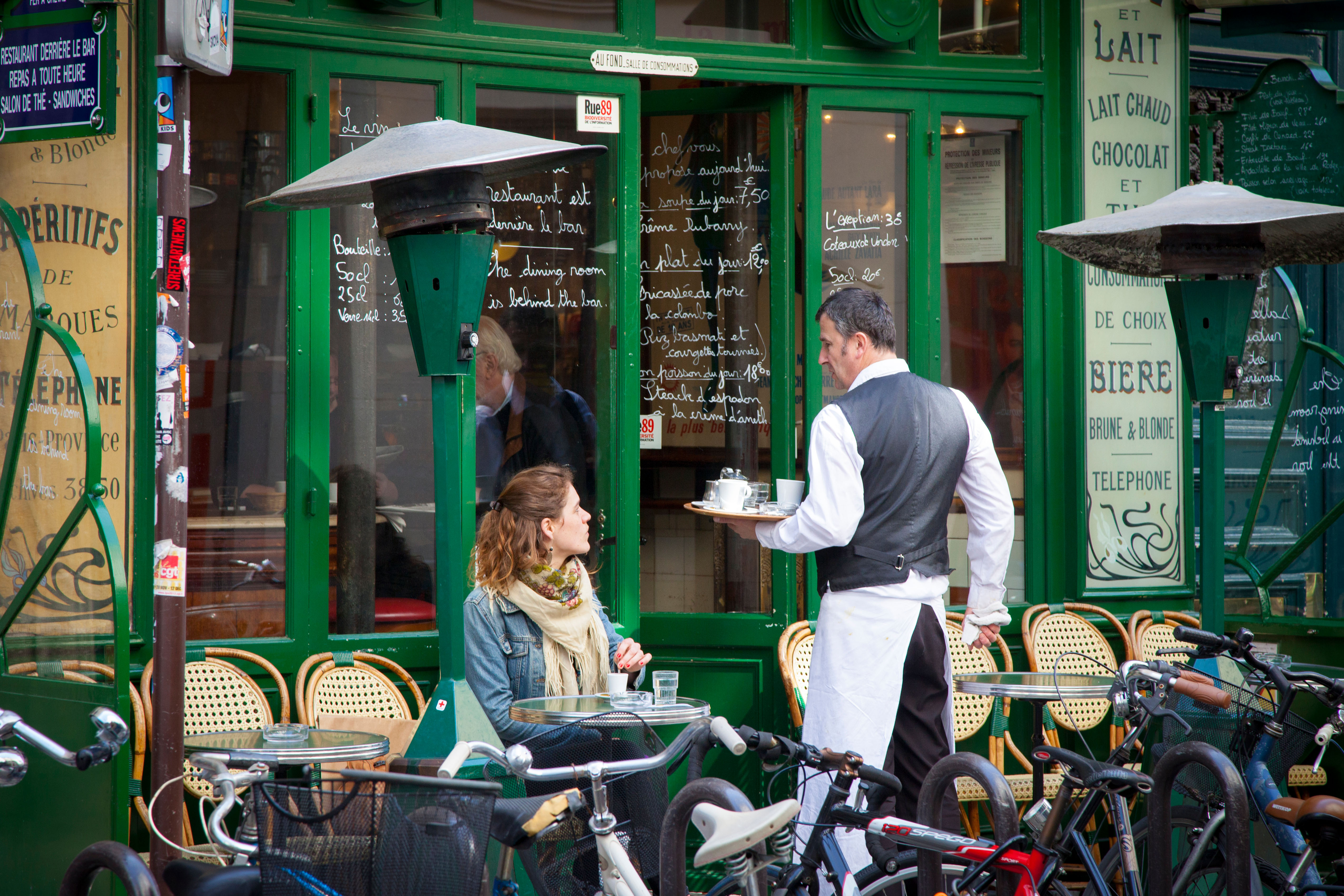 Waiter serving a customer at a Parisian cafe.