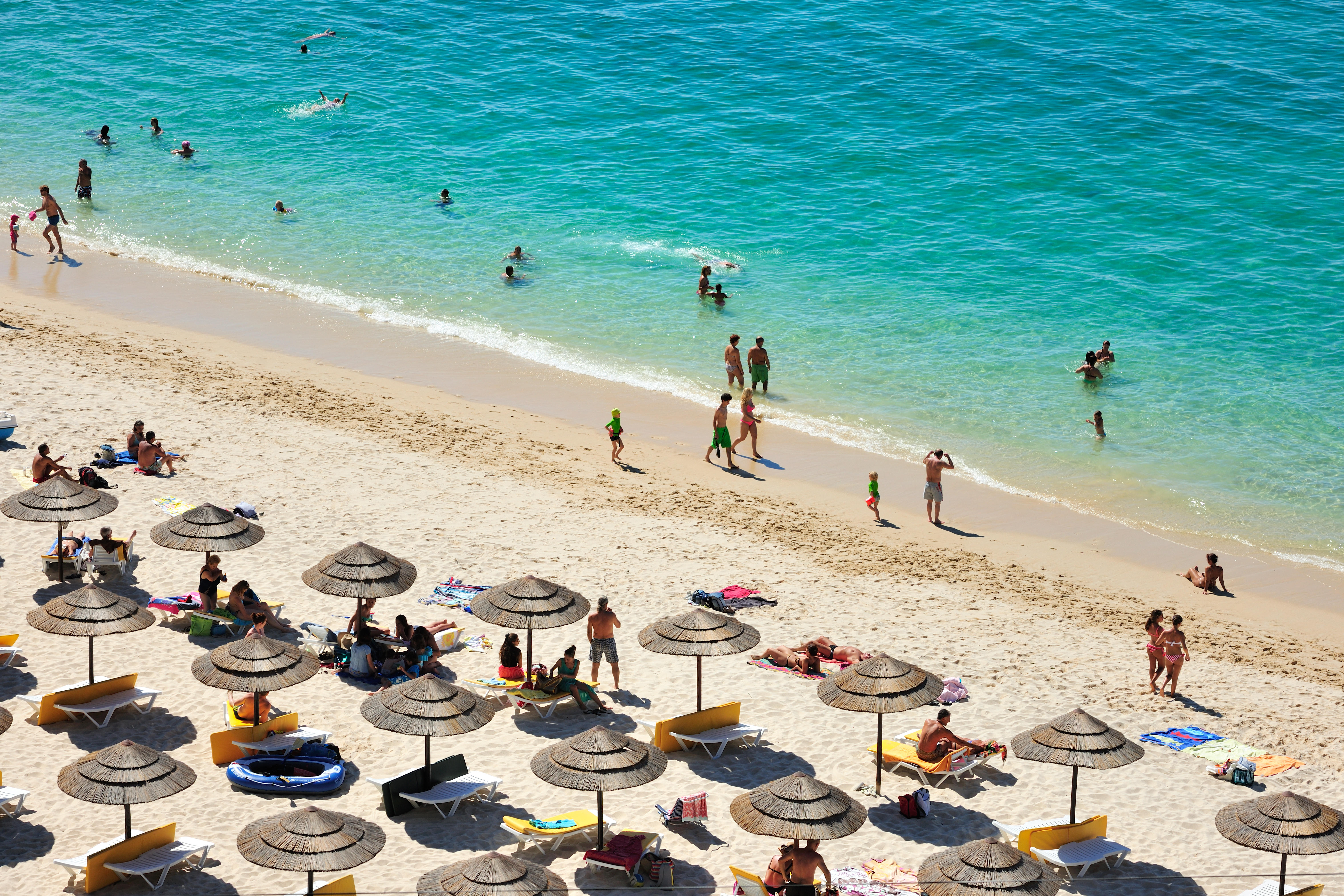 Aerial view of Galapos beach in Arrabida Natural Park, Portugal, showing people swimming and sunbathing.