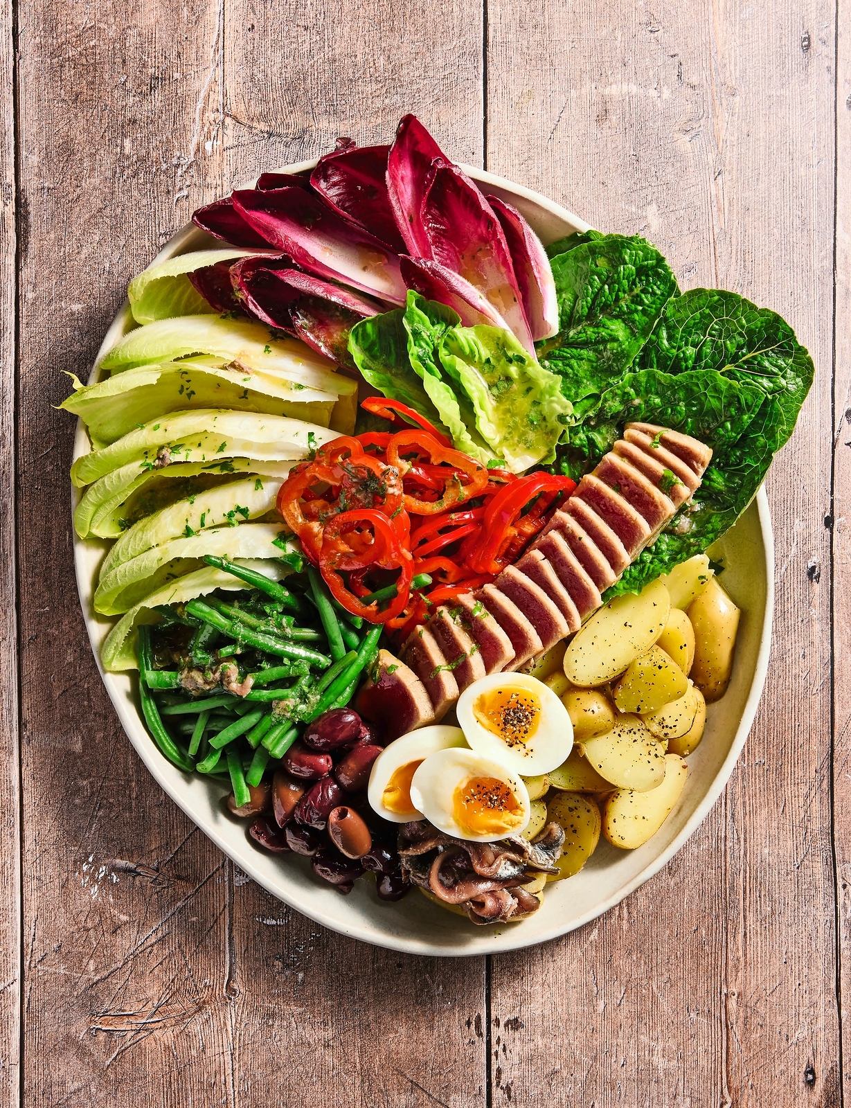 Nicoise salad with tuna, eggs, green beans, olives, and various lettuces.