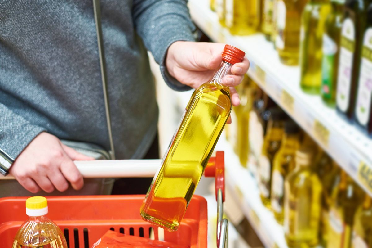 Bottle of olive oil in the hand of the buyer at the grocery store.
