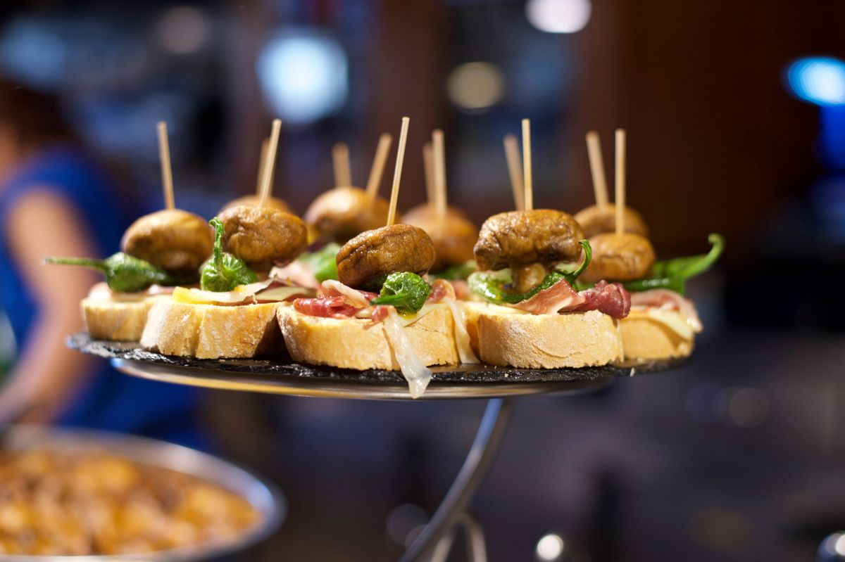 Pintxos are a regional version of Spanish tapas, served in bars in the Basque region. Usually secured with a cocktail stick and served in bread.In a bar in Gernika, these pintxos (pinchos) are made of mushroom, peppers and Iberico ham (Jamon Iberico).