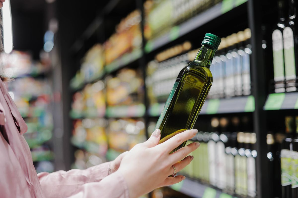 Woman choosing natural olive oil or grape seed oil at store. Concept of healthy food, bio, diet.