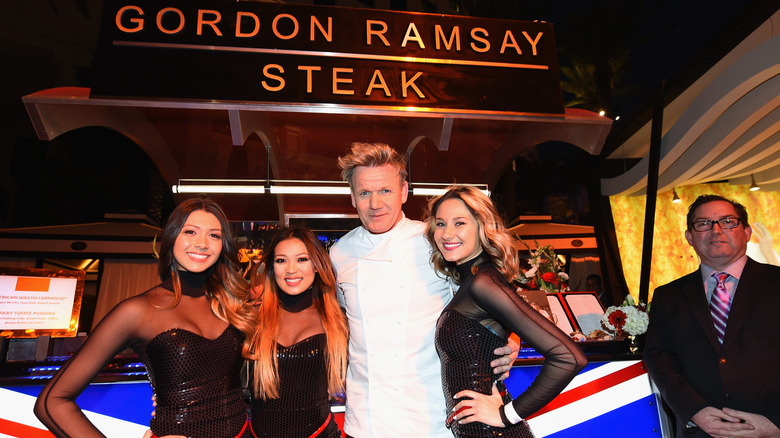 Gordon Ramsay poses with models outside of Gordon Ramsay Steak entrance and signage in Las Vegas