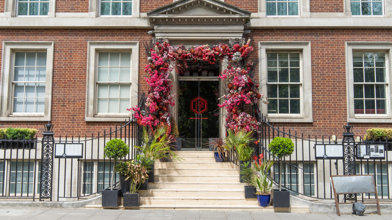 Outside of Gordon Ramsay Bar & Grill in Mayfair in brick building with white steps leading to doorway framed by plants and flowers