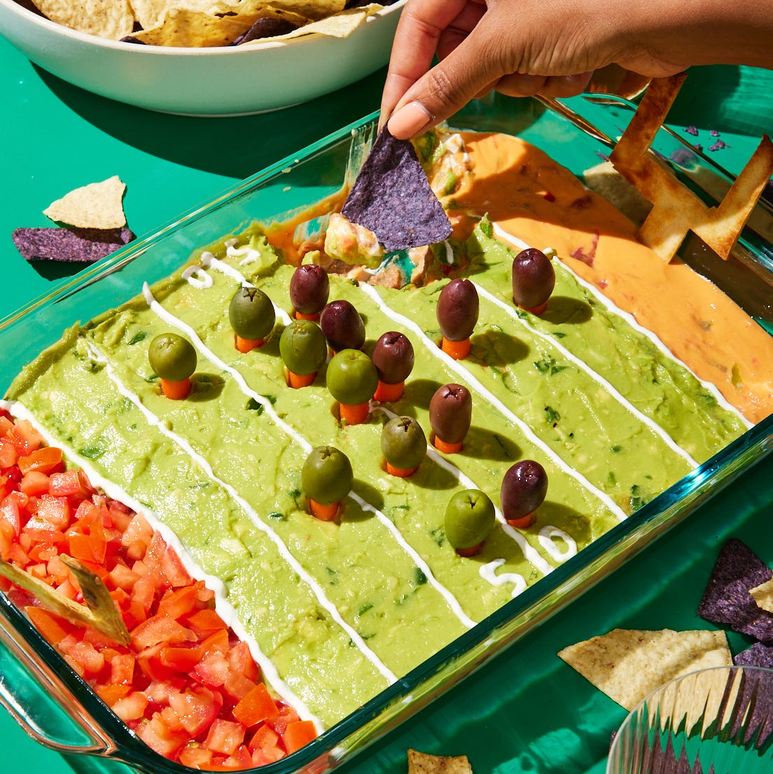 football field decorated layered dip with refried beans, sour cream, pico de gallo, guacamole, and queso