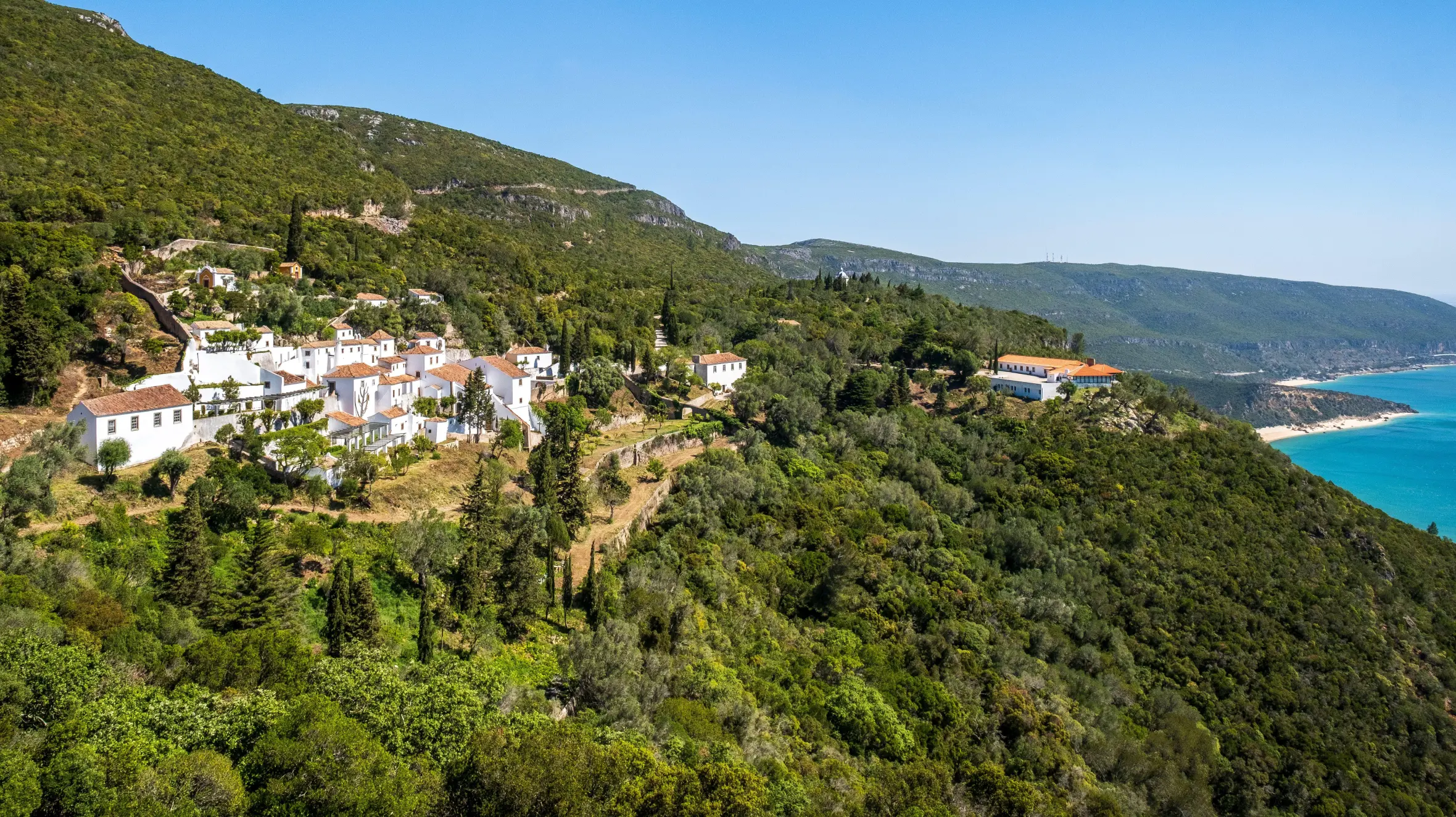 Monastery of Nossa Senhora da Arrábida on a hillside overlooking the ocean.