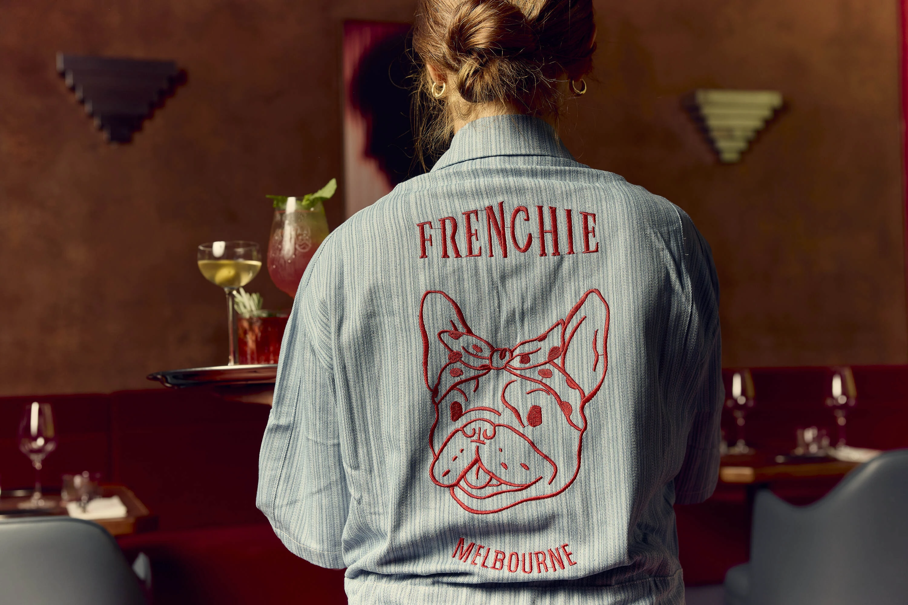 Frenchie staff member serving a tray of drinks.
