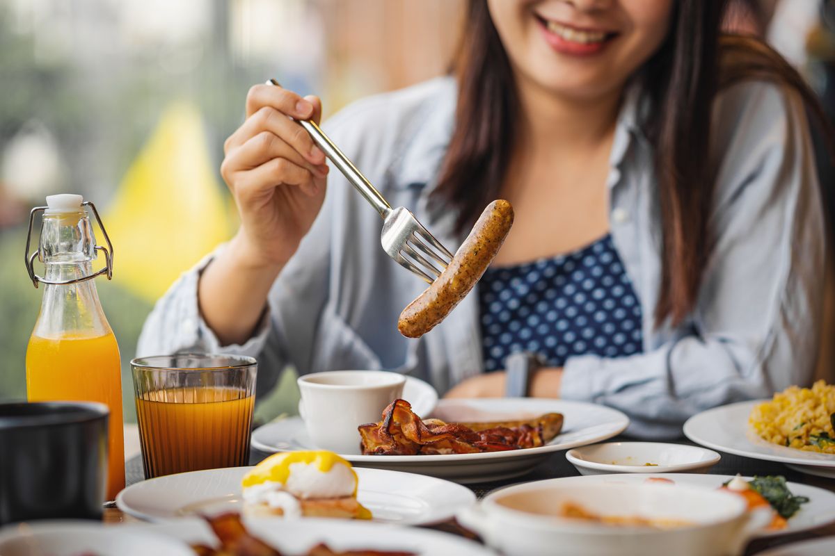 Woman eating sausage for breakfast