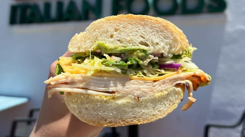 A person holding an Italian sub from Mona Lisa Italian Foods in San Diego