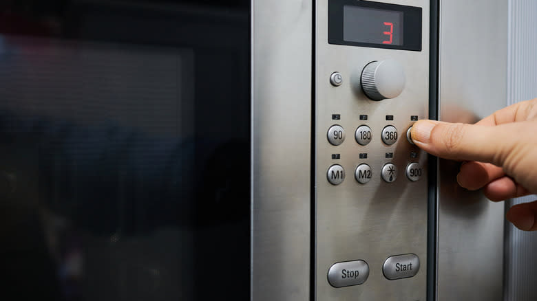 Up close shot of a hand setting a microwave