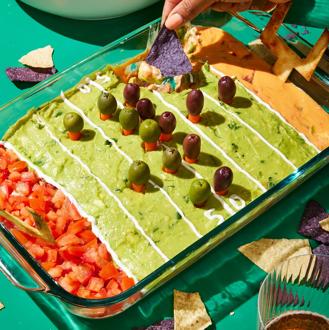 football field decorated layered dip with refried beans, sour cream, pico de gallo, guacamole, and queso
