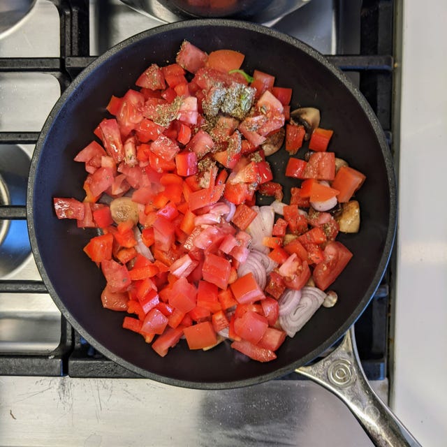 Chopped tomatoes, onions, and spices in a frying pan.