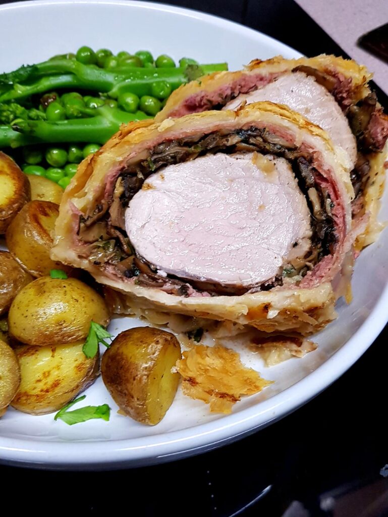 Pork Wellington with Sautéed Potatoes, Brocolli and Mushroom Gravy. Made with Pork Tenderloin, Homemade Patê, Prosciutto and Mushroom Duxelles.