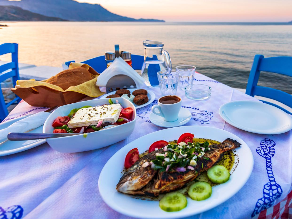 Plates of food on a table near the water in Create, Greece.