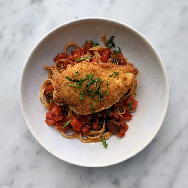 Plate of pasta with breaded chicken and vegetables.