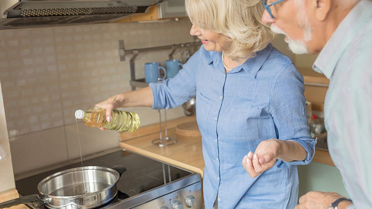 Older woman and her husband cooking with olive oil