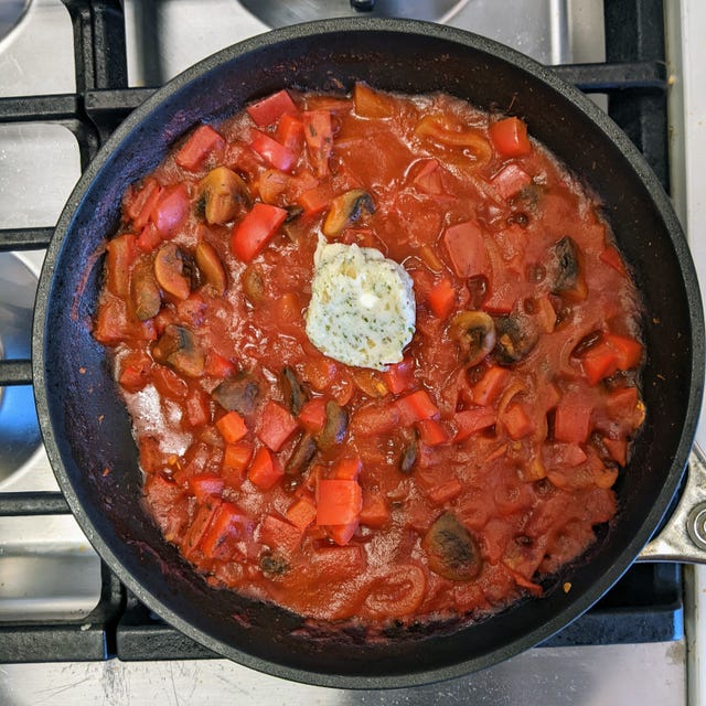 Sautéed vegetables in a skillet with a dollop of herb butter.