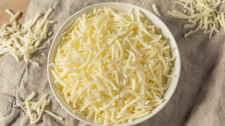 View from above of a white bowl filled with shredded mozzarella cheese