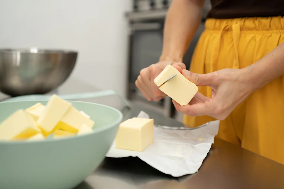 woman holding and cutting butter with a knife in kitchen