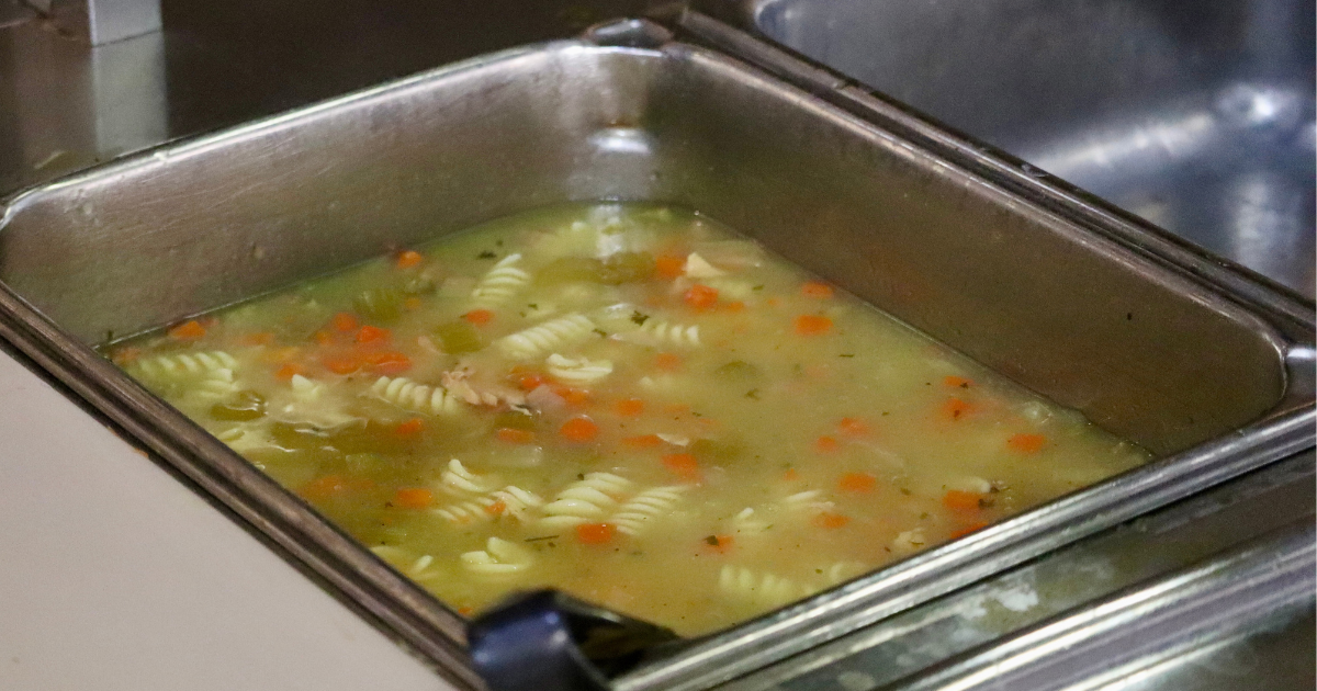 A metal tray filled with rotini chicken noodle all you can eat soup Michigan at a restaurant buffet.