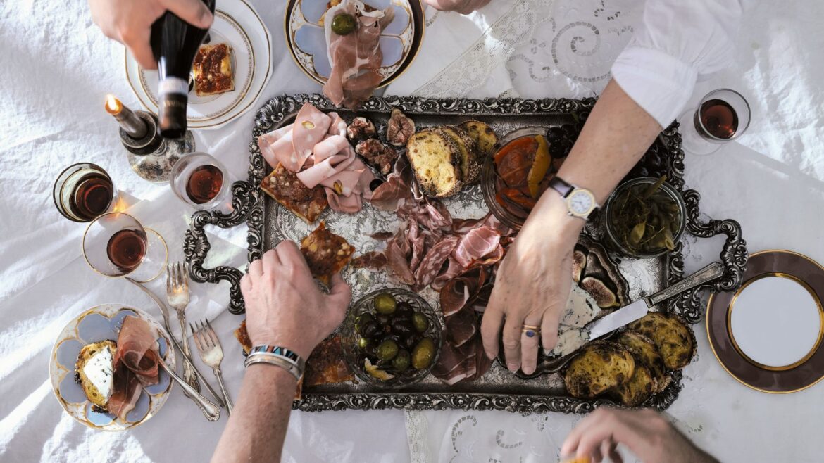 hands reaching at food on an antipasti board