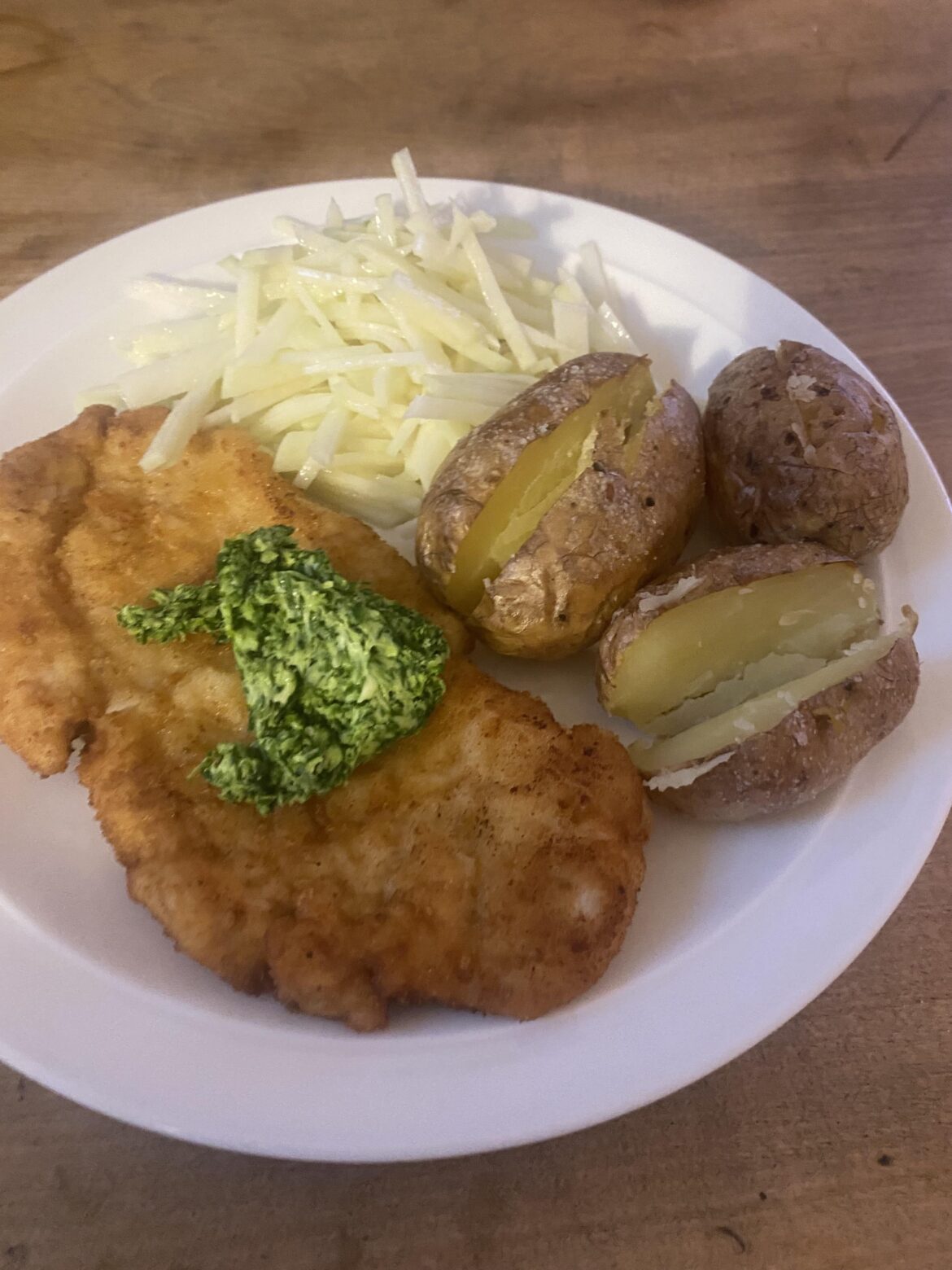 Chicken schnitzel with wild garlic butter, roast potatoes and kohlrabi slaw