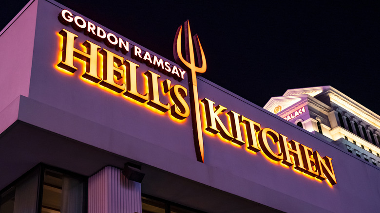 Exterior of Gordon Ramsay Hell's Kitchen below Caesar's Palace in Las Vegas, restaurant signage lit up at night including devil's trident