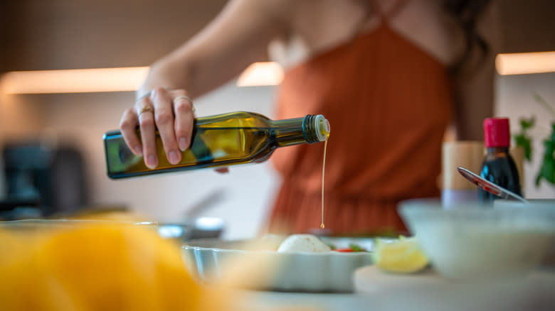 person pouring olive oil on dish