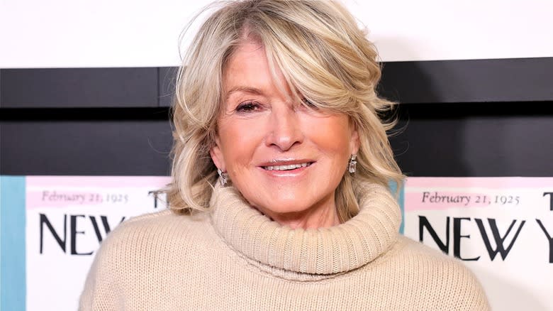 Martha Stewart smiling in a taupe-colored fold-over turtleneck sweater