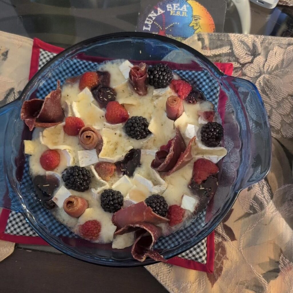 la bonne vie triple cream baked brie with raspberries, blackberries, prosciutto, raspberry jam, drizzled honey and rosemary