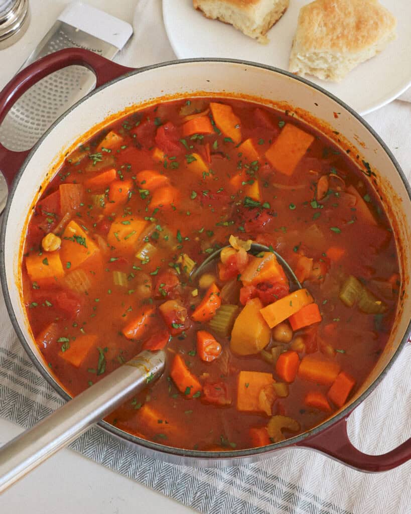 An overhead view of a Dutch oven and a ladle full of chickpea soup.