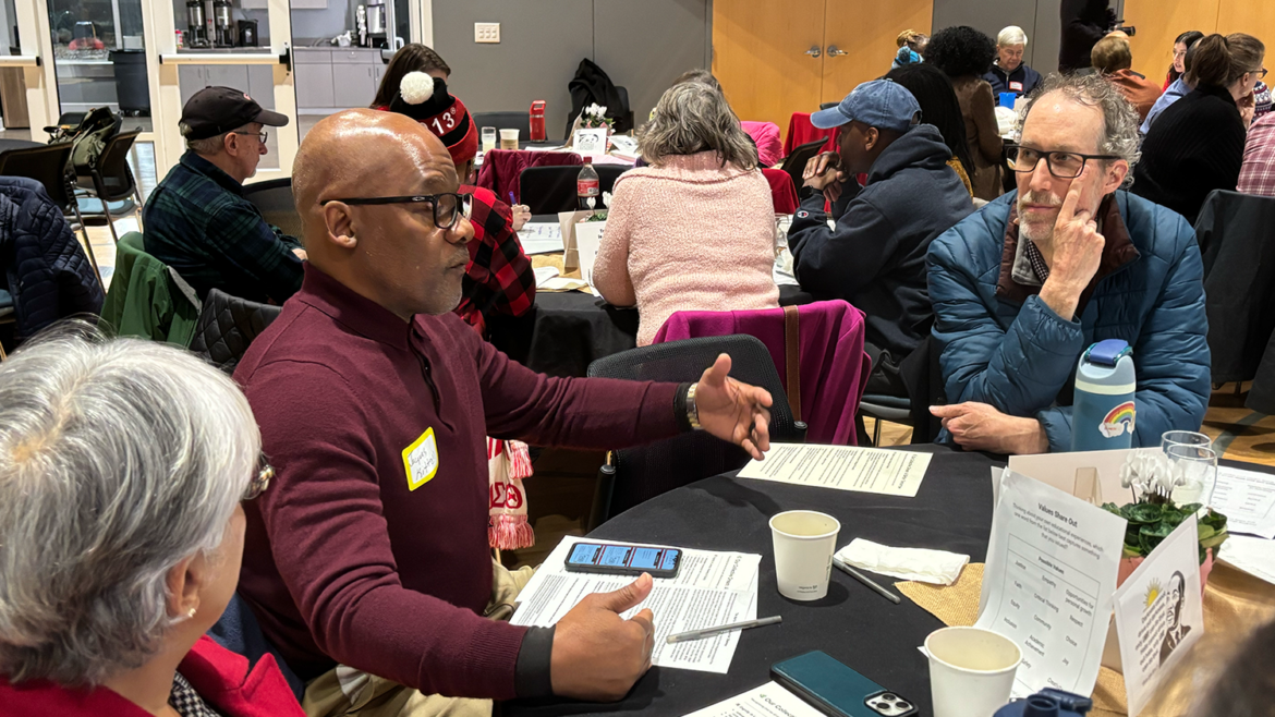 A group of people work together around a table at the Dining with Democracy event in Cary, North Carolina.