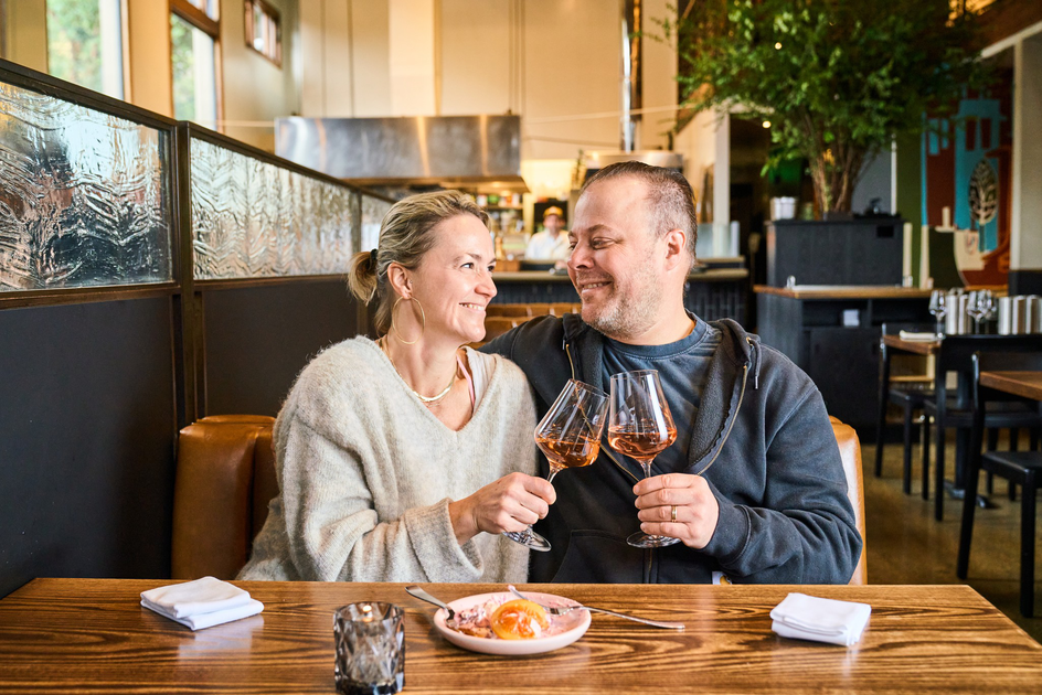 The best date-night restaurants in SF, according to a panel of restaurant pros A couple sits closely at a restaurant table, smiling and clinking glasses of rosé wine, with a dessert dish in front of them.