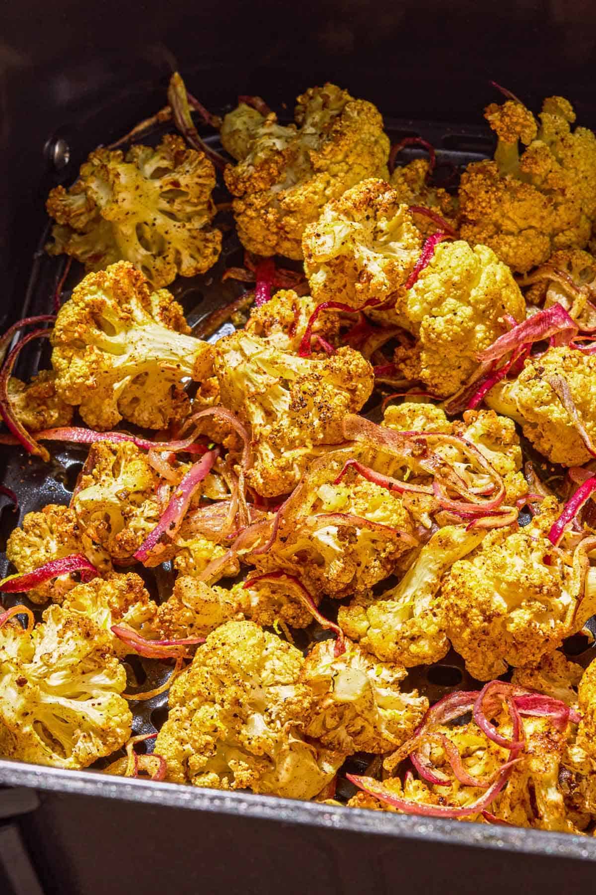 Air fryer cauliflower in the basket of an air fryer.