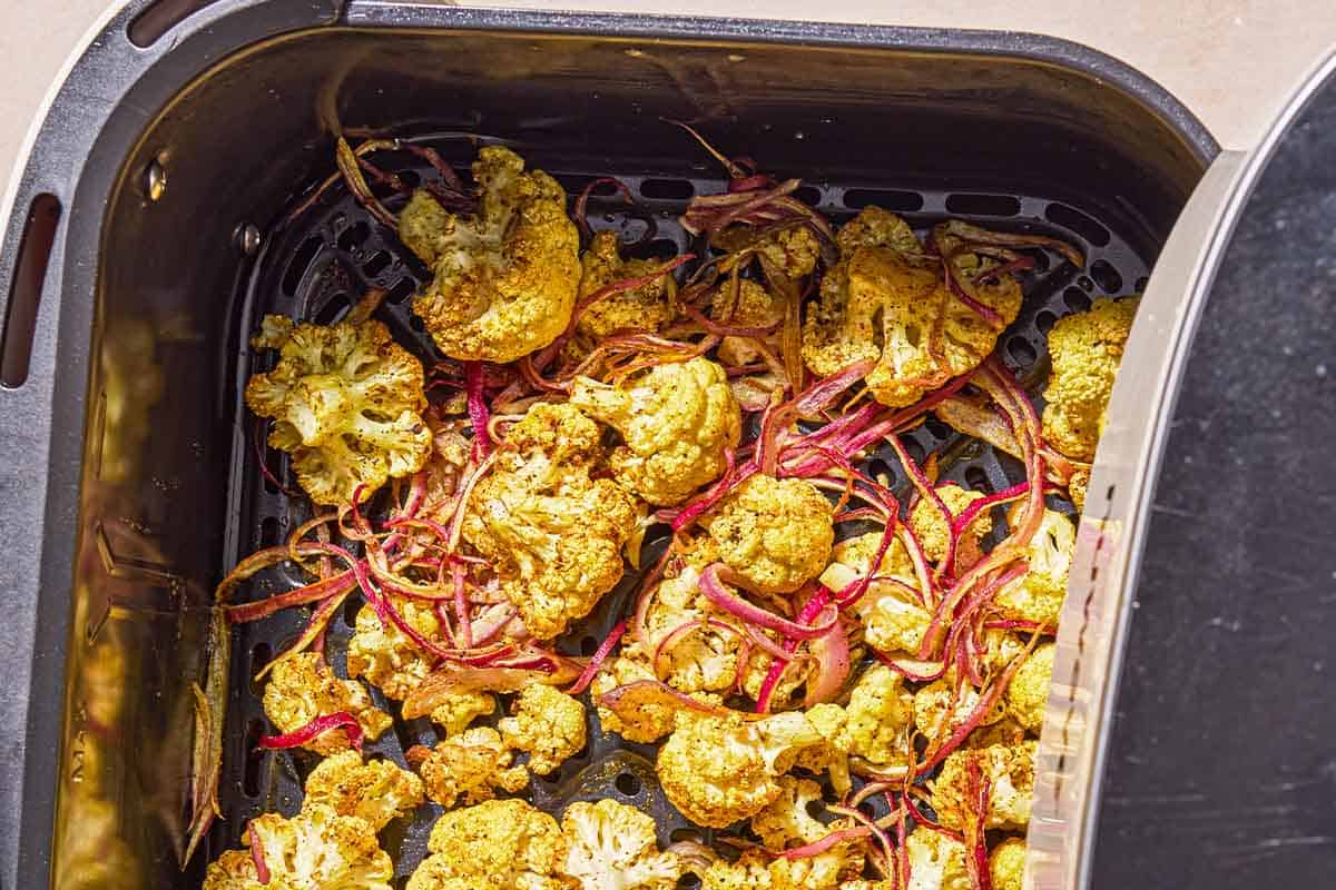 Air fryer cauliflower in the basket of an air fryer.
