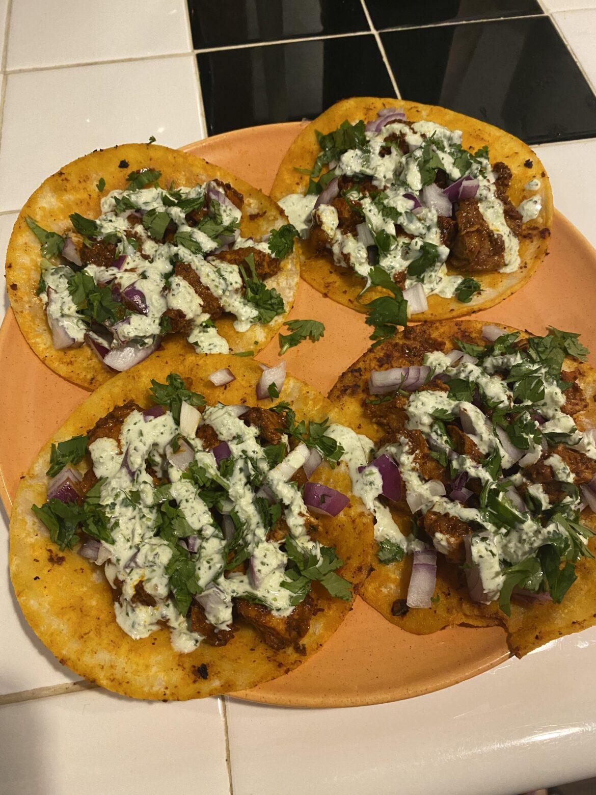 Homemade al pastor tacos with diced red onion, cilantro, and a cilantro lime crema.